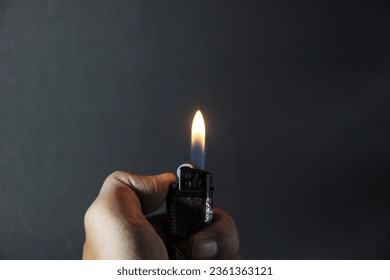 close up photo of a hand lighting a match, with a black background