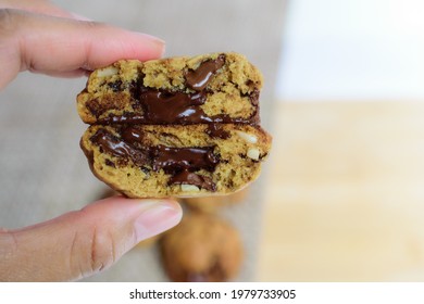 Close Up Photo Of The Hand That Picked Up The Chocolate Chip Cookie It Is Had A Gooey Filling And Look Very Delicious.