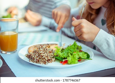 Close Up Photo Of Hands Of Child Girl Eating Healthy Dinner With Fresh Salad, Quinoa And Fish On Terrace