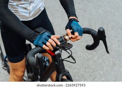 Close photo, hands of male cyclist in outfit on hand and bicycle computer. Background. Cycling sport concept - Powered by Shutterstock