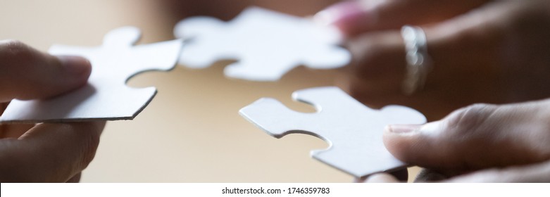 Close up photo hands of multi ethnic people hold diverse pieces of puzzle, team assembling jigsaw joining fragments, teamwork, search find solution concept. Horizontal banner for website header design - Powered by Shutterstock