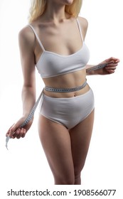 Close up photo of healthy woman with slim belly measuring her waist's size