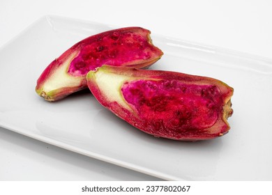 Close up photo of the interior of a prickly pear cactus fruit cut in half on a plate with seeds
