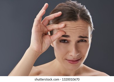 Close Up Photo Of Lady With Naked Shoulders Standing Isolated On Gray Background And Squeezing Her Forehead To Checking Wrinkle