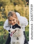 Close up photo of a little blond girl hugging her pet dog outdooors on nature in summer. Yakutian Laika dog breed. Happy childhood concept. Summertime