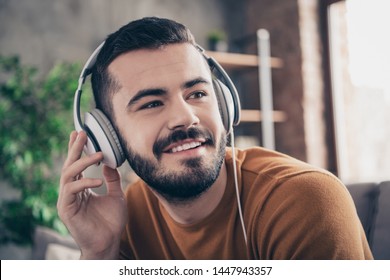 Close up photo of lovely handsome trendy stylish man hold hand use modern technology hear favorite soundtrack sound track orange pullover sweater sit divan couch room - Powered by Shutterstock