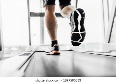 Foto de cerca de los pies masculinos en una cinta de correr. Cardio.