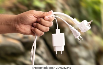 Close up photo of man holding multiple unplugged charging sockets. Concept of energy saving and reduce electricity usage. - Shutterstock ID 2140782245