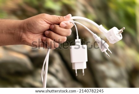 Close up photo of man holding multiple unplugged charging sockets. Concept of energy saving and reduce electricity usage.