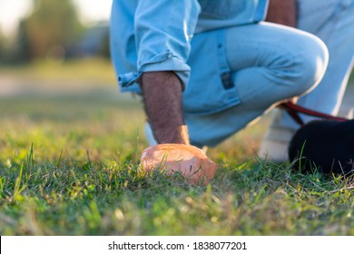 Close Up Photo Of Man Picking Up Dog Poop From The Lawn At The Public Park. Pet Owner Picks Up Dog's Poop Cleaning Up Mess. 