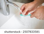 Close up photo of man washing toothbrush after using	