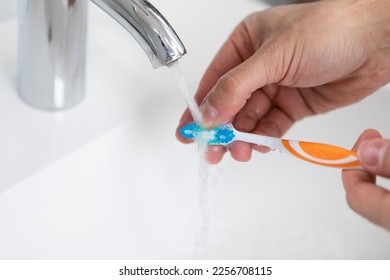 Close up photo of man washing toothbrush after using - Shutterstock ID 2256708115