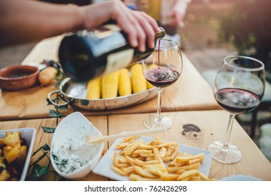 Close up photo of men pouring red wine into a glass at backyard patio - Powered by Shutterstock