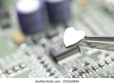 A close up photo of metal heart is being installed into a circuit board.