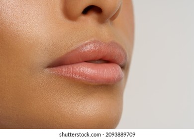 Close up photo of moisturized smooth lips of african american woman using chapstick or moisturizing lip balm to nourish, hydrate and protect from cold. Winter skincare and chapped lip prevention