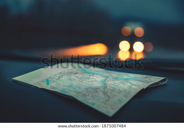 Close Up Photo on a Map used\
in the Car. Automobile Lights on the Highway at Night. Traveling\
Concept