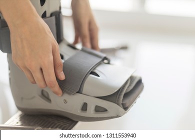 Close Up Photo Of Orthopedic Walking Boots That Selective Focus At Forefoot Strap. The Walking Cast Use In Woman Patient With Ankle Injury, Fracture Or Ankle Sprain. Patient Sitting On Wheel Chair.