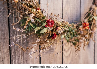 Close Up Photo, Part Of Twisted Crafting, Arvensis Creative Dry Herbal Wreath From Twigs Of Wild Flowers, Cereal And Grass. Traditional Festive Ethnic Decoration On Entrance Door. Low Angle View