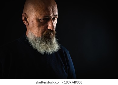 foto de primer plano, retrato de un hombre serio, reflexivo, barbudo sobre un fondo oscuro, seguro de sí mismo y con un aspecto dramático recto. Concepto de retrato masculino.  Tecla baja 