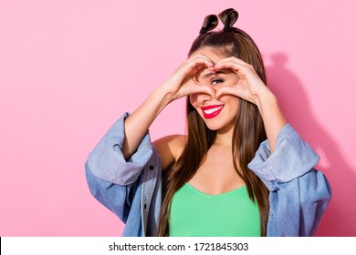Close up photo of positive cheerful girl teen make heart shape love symbol figure watch eye face look after her boyfriend wear green cropped top isolated over pastel color background
