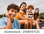 Close up photo of positive multiracial teenagers high school pupils friends classmates college students boys and girls hanging out together in urban street park sport court outside looking at camera