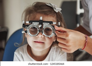 Close up photo of a pretty little girl with glasses have testing her eyes.