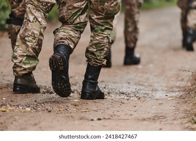 Close up photo, the resilient legs of elite soldiers, clad in camouflage boots, stride purposefully along a hazardous forest path as they embark on a high-stakes military mission - Powered by Shutterstock