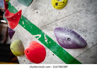 Close Up Photo Of A Rock Climbing Wall With Climbing Holds In Gym. 