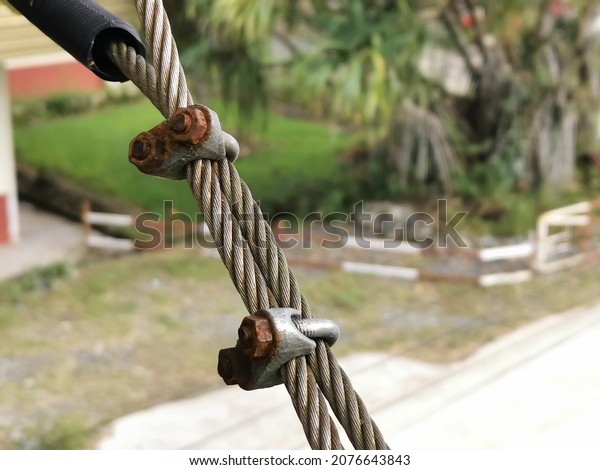 Close\
up photo of rusty wire rope clamps and steel\
rope.