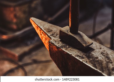 Close up photo shoot of hammer and anvil at dark smith workshop.