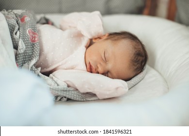 Close Up Photo Of A Sleeping Newborn Baby In Warm Clothes Covered With A Quilt In Her Bed