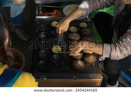 Close up photo of street food person making Banh Can, Vietnamese rice flour pancake
