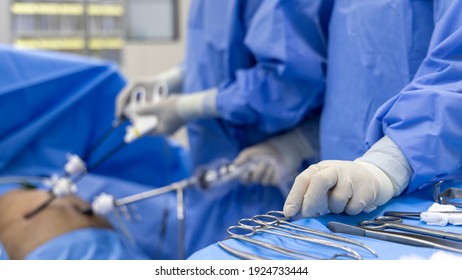 Close up photo of surgeon 's hands inside modern operating room in blue surgical gown suit with blur background.Scrub nurse send surgical instrument to surgeon in key hole surgery.Medical concept.