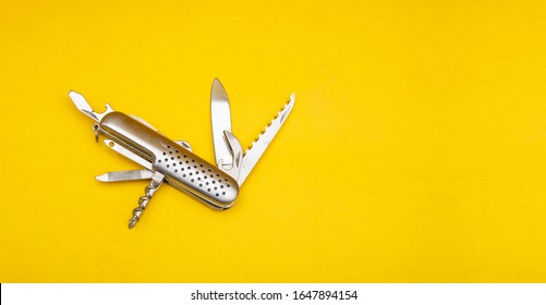 Close up photo of swiss army knife on yellow background with copy space
