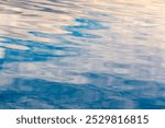 Close up photo of waves on the surface blurred ripples. Transparent defocus blue color water with ripples spreading in a shiny pattern on the surface background.
