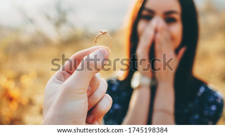 Close up photo of a wedding ring with diamond shown to the girl while she is amazed and covers her face with palms