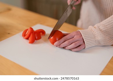 Close up photo of woman cutting tomato on white cutting board - Powered by Shutterstock