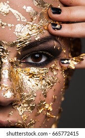 Close Up Photo Of A Woman With A Gold Mask On Her Face On A Gray Background