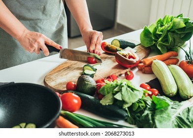 Close Up Photo of Woman Hands Cutting Fresh Vegetables on a Wooden Cutting Board in Kitchen - Powered by Shutterstock