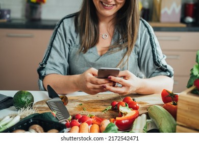 Close Up Photo Of Woman Hands Using Mobile Phone While Making Healthy Lunch In The Kitchen