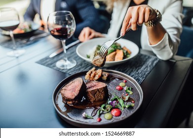Close up photo, woman ready to eat medium rare beef steak while sitting in modern restaurant.