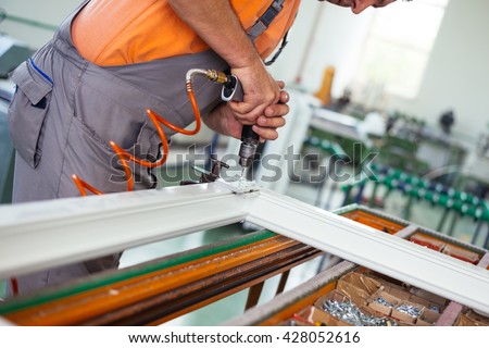 Close up photo of workers hands assembling PVC doors and windows. Selective focus. Factory for aluminum and PVC windows and doors production.