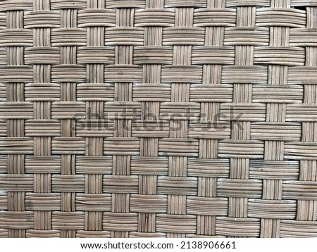 Close up photo of a worn, beige, outdoor,  woven, ratan chair.