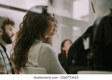 A close up photo of young gorgeous business girl with a curly hair listening to her colleague talking - Powered by Shutterstock