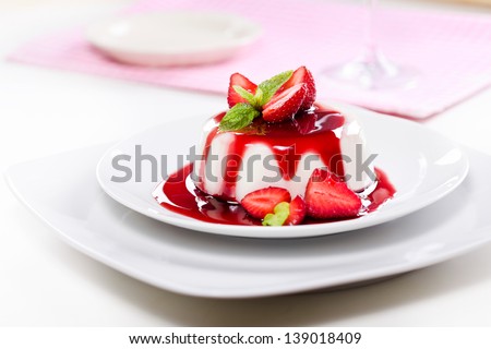 Close up photograph of a fancy panna cotta with strawberries