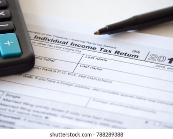Close up photograph of individual income federal tax return paperwork with calculator and black ballpoint pen at borders for a nice tax season background, backdrop or wallpaper image. - Shutterstock ID 788289388