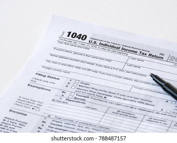 Close up photograph of United States 1040 individual income tax return form with a black ballpoint pen perfect for tax day or tax season background or wallpaper image.