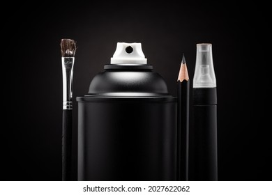 Close up photograph of various art utensils such as a black spray paint can, a brush, a pencil and a marker on a black background. Represents various techniques that can be used to make art.