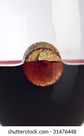 Close up photograph of a wine bottle cork floating in a glass of wine