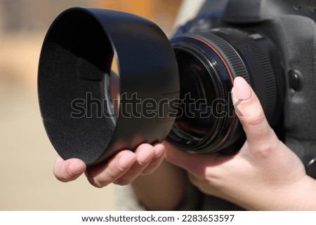 Close up of a photographer hand installing lens hood outdoors